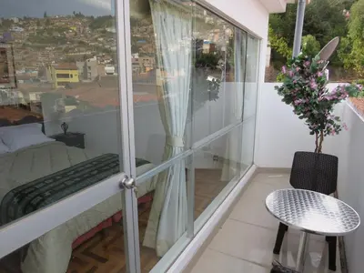 a balcony with a bed and a table at Apartamentos Quewe in Cusco