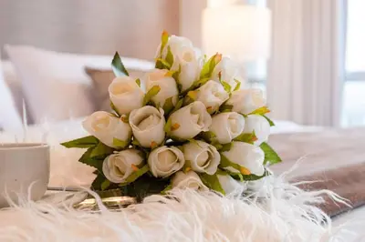 a bouquet of white roses on a table with a cup at OceanFront Larcomar Apartments in Lima