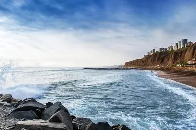a beach with waves crashing on the rocks at OceanFront Larcomar Apartments in Lima