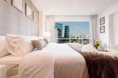 a bedroom with a large white bed with a large window at OceanFront Larcomar Apartments in Lima
