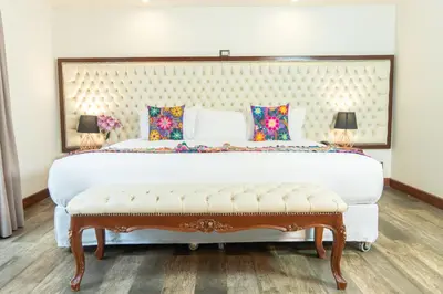a bedroom with a large white bed with a bench at Jaya Machu Picchu Boutique Hotel in Machu Picchu