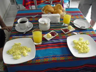 a table with plates of food and cups of orange juice at Kelebek Hostel in Lima