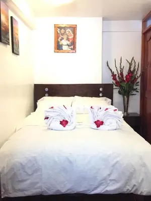 a bed with white sheets and red flowers on it at Hospedaje Qori Punku in Cusco