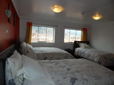 a bedroom with two beds and a window at Hospedaje Qori Punku in Cusco