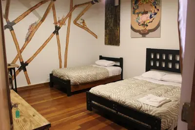 two beds in a room with wooden floors at Hommam in Cusco