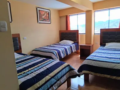 a hotel room with two beds and a window at Hostal Kuntur Cusco in Cusco