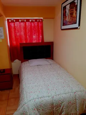 a bedroom with a bed and a red window at Hostal Kuntur Cusco in Cusco