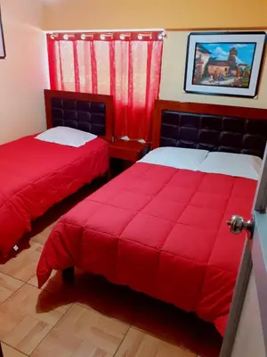 a bedroom with two beds with red covers and a window at Hostal Kuntur Cusco in Cusco