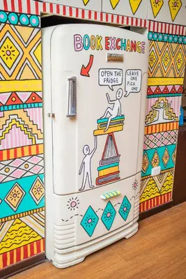 a book exchange door in a classroom with a refrigerator at Pariwana Hostel Lima in Lima