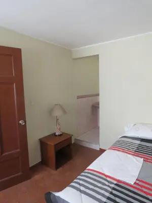 a bedroom with a bed and a table with a lamp at Casa particular de Jorge Edinson in Lima