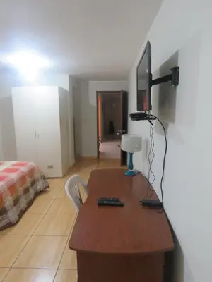 a room with a desk with a television and a bed at Casa particular de Jorge Edinson in Lima