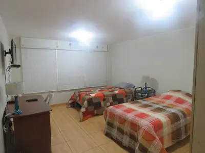 a room with two beds and a table in it at Casa particular de Jorge Edinson in Lima
