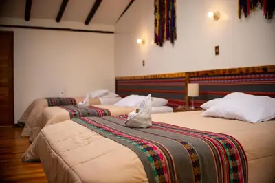 a group of four beds in a room at Casita Huaran in Calca