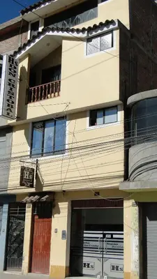 a white building with a balcony and a door at Hostal Don Cristobal in Ayacucho