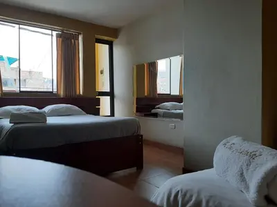 a hotel room with two beds and a window at Hostal Don Cristobal in Ayacucho