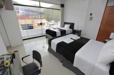 two beds in a room with a large window at Hotel Murano in Abancay