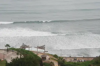 a view of the ocean with people surfing in the waves at Black Shark Apartments in Lima