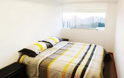 a bed in a white room with a window at Departamento Lima in Lima