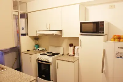 a kitchen with white cabinets and a white stove and refrigerator at Departamento Lima in Lima