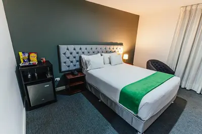 a hotel room with a large bed with a green blanket at Hotel Hacienda Lima Norte in Lima