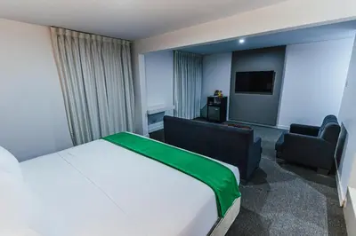 a hotel room with a bed and a chair at Hotel Hacienda Lima Norte in Lima