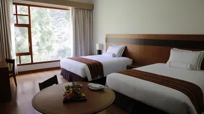 a hotel room with two beds and a table at Taypikala Deluxe Valle Sagrado in Urubamba