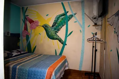 a bedroom with a bird painting on the wall at Passion Hostel - Barranco in Lima