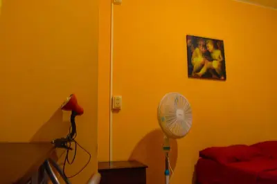 a yellow room with a fan and a picture on the wall at Passion Hostel - Barranco in Lima