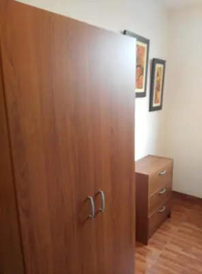 a large wooden cabinet in a room with a dresser at White Hope Apartment in Lima
