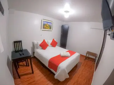 a bedroom with a white bed with red pillows at Machu Picchu Land in Machu Picchu