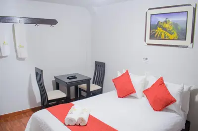 a bedroom with a bed with red pillows and a table at Machu Picchu Land in Machu Picchu