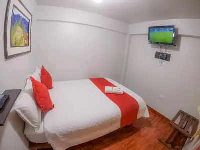a bedroom with a bed with a television on the wall at Machu Picchu Land in Machu Picchu
