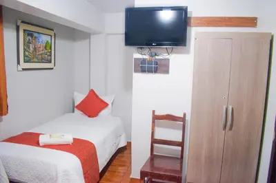 a small room with a bed and a tv on the wall at Machu Picchu Land in Machu Picchu