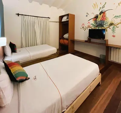 a room with two beds and a tv in it at Usgar San Pedro Boutique in Cusco