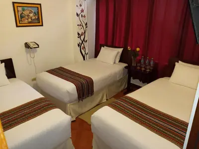 two beds in a hotel room with red curtains at Inkas Land in Machu Picchu