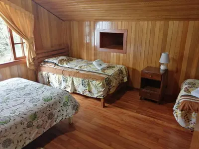 a bedroom with two beds and a table with a lamp at Illariy Tampu Ecoalbergue Oxapampa in Oxapampa