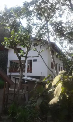 a white house with a tree in front of it at Illariy Tampu Ecoalbergue Oxapampa in Oxapampa