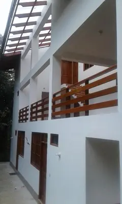 a white building with wooden doors and stairs at Illariy Tampu Ecoalbergue Oxapampa in Oxapampa