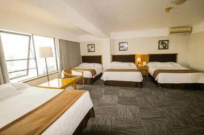 a hotel room with four beds and a large window at Hotel Miramar in Lima