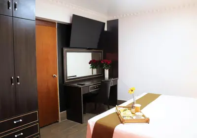 a bedroom with a bed and a dressing table and a mirror at Inkari Suites Hotel in Lima