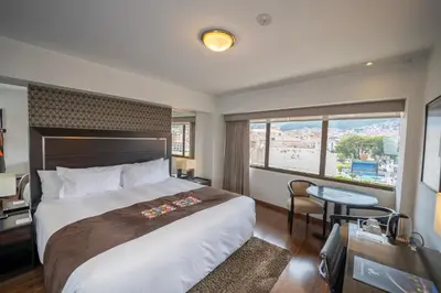 a hotel room with a large bed and a desk at Hotel Jose Antonio Cusco in Cusco