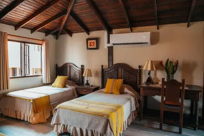 a bedroom with two beds and a desk and a window at Hotel Antigua Miraflores in Lima