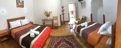 a hotel room with two beds and a table at Casa Union Cusco in Cusco