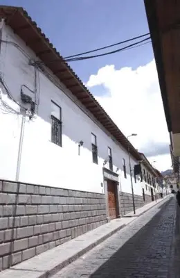 a white building with a brick sidewalk next to a street at Casa Union Cusco in Cusco