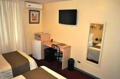 a hotel room with a desk and a television on the wall at Embajadores Hotel in Lima