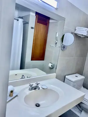 a bathroom with a sink and a toilet and a mirror at Faraona Grand Hotel in Lima