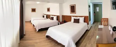 a hotel room with two beds with white sheets at Faraona Grand Hotel in Lima