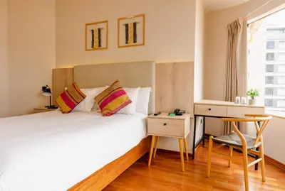 a bedroom with a bed and a desk and a bed and a window at Torre Dorada Cusco in Cusco