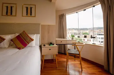 a hotel room with a bed and a desk and a window at Torre Dorada Cusco in Cusco