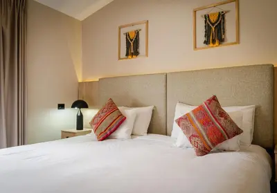 a bedroom with a white bed with two pillows at Torre Dorada Cusco in Cusco